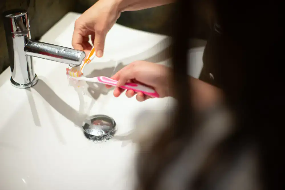 Close up of a child using a colorful toothbrush under supervision