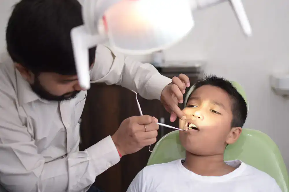 Dentist gently examining a smiling child's teeth